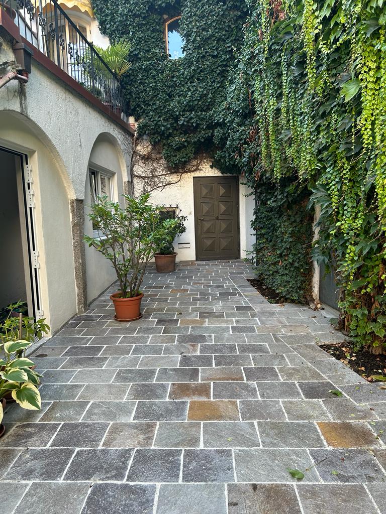 Innenhof Quarzit Grüner Innenhof in Steinoptik mit Tor am Ende