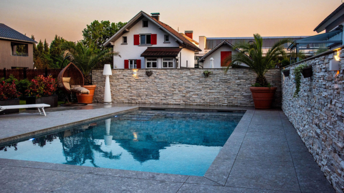 Pool mit Steinmauer und Haus im Hintergrund